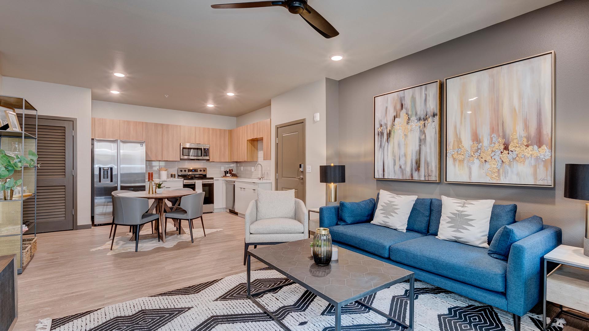 Living room with wood floors, rug, plush couch, modern furnishings, and large artwork.