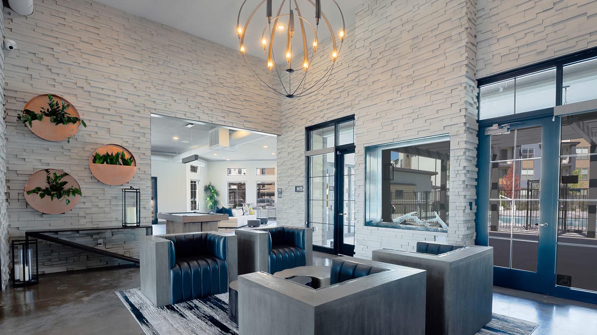 Clubhouse with stone walls, decorative copper planters, chandelier, and modern chairs.