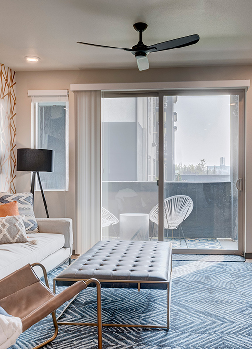 Living room with wall mounted TV, geometric wallpaper, plush furniture, and door to balcony.